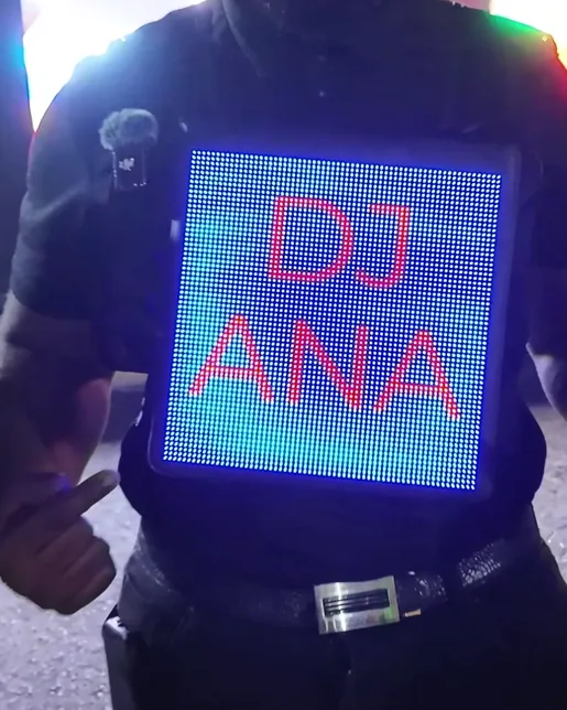 A Timesquare LED vest at a night event, its pixel screen reading DJ ANA